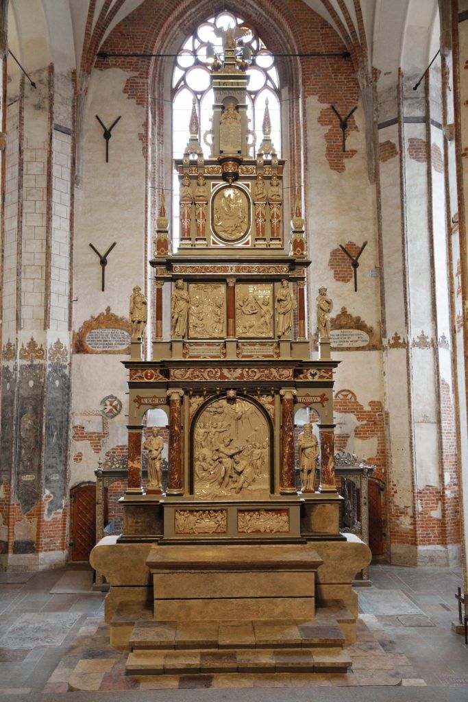 Wnętrze kościoła św. Jana w Gdańsku. Zdjęcie przedstawia kamienny, bogato rzeźbiony w sceny biblijne ołtarz główny. 